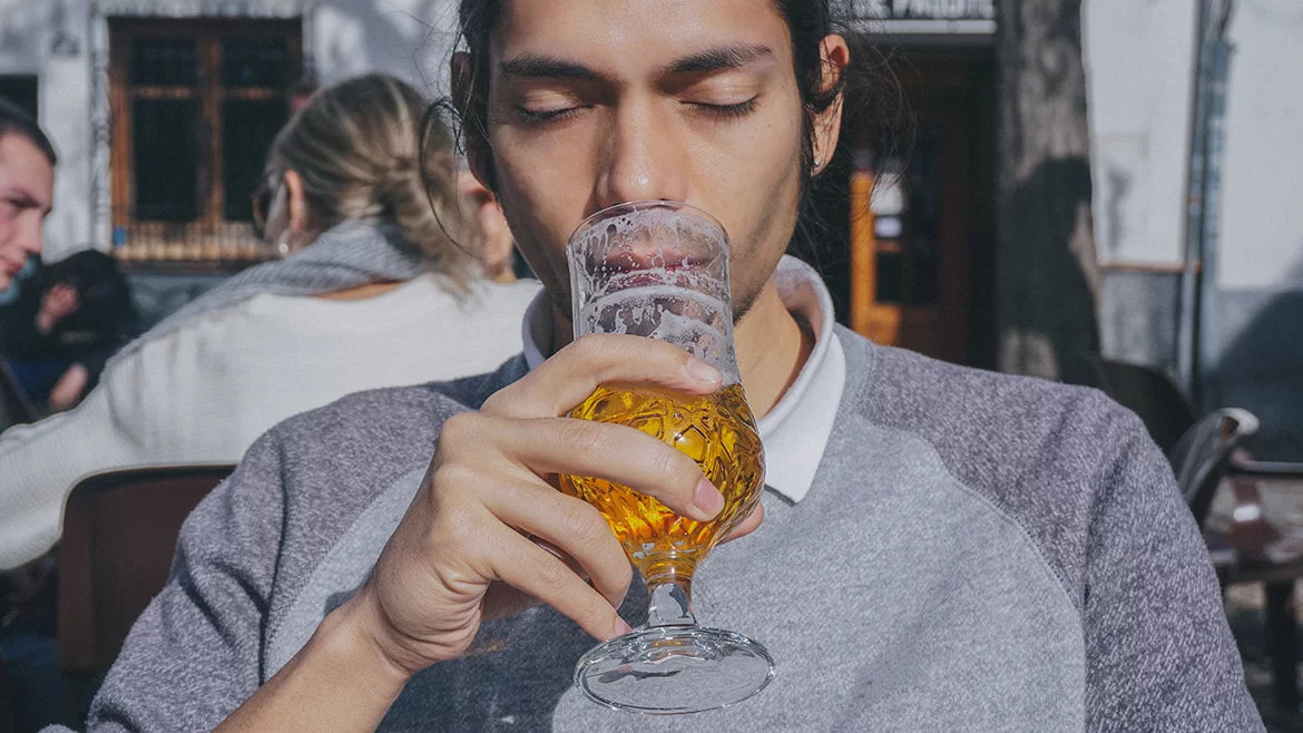 A man drinking a glass of hemp beer outdoors