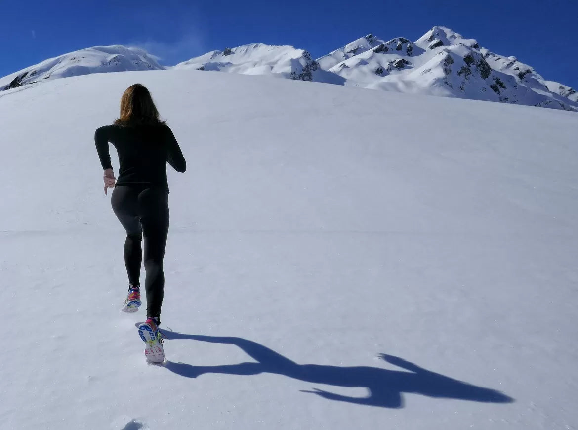 A woman running up a snowy mountain