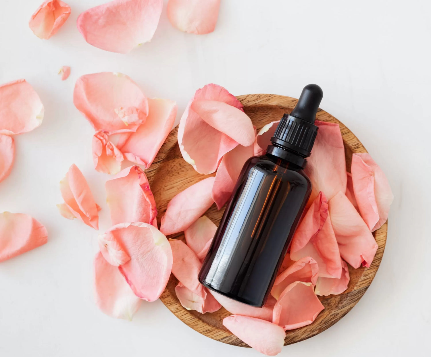 A vial of CBD hemp oil rests on rose petals