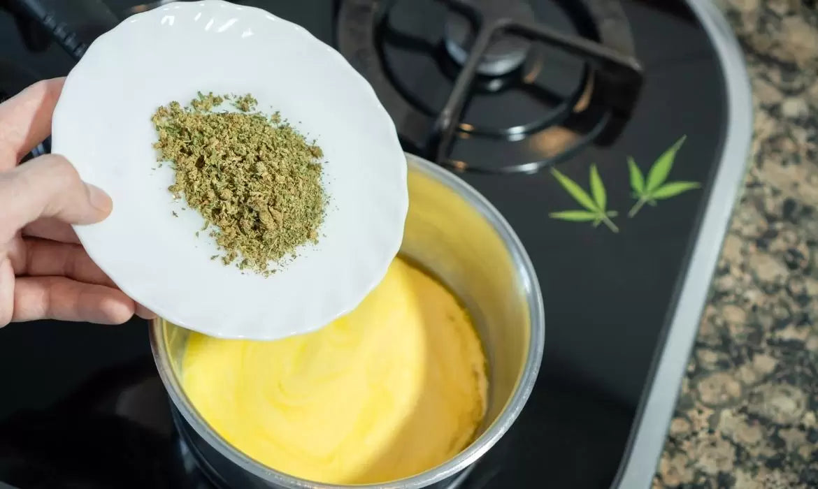 Cannabis kief being dropped from a white plate into a pot with melting butter.