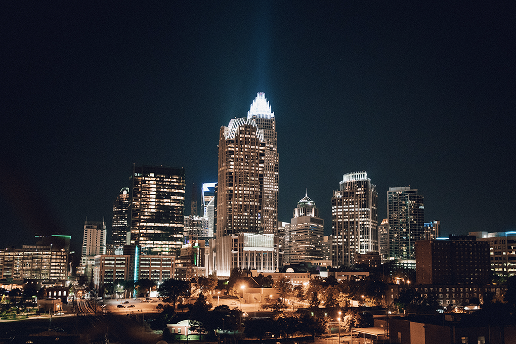 A night view of high-rise and small buildings in Charlotte, North Carolina, with glowing lights