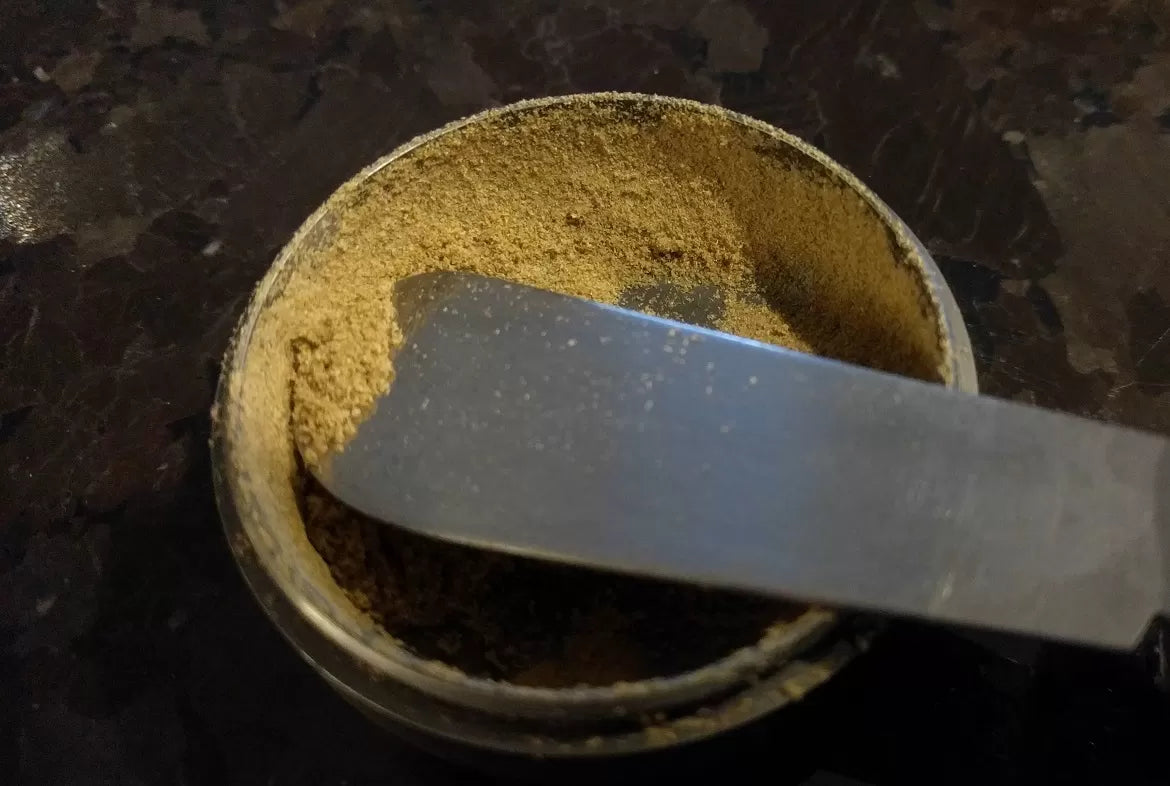 Hemp kief on a knife in a grinder