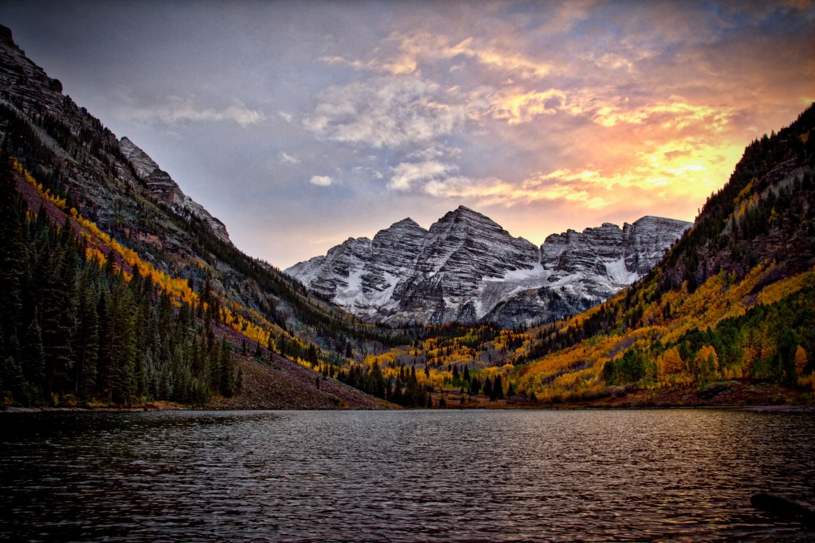 A beautiful sun sets over a lake surrounded by mountains in Moonbells Colorado